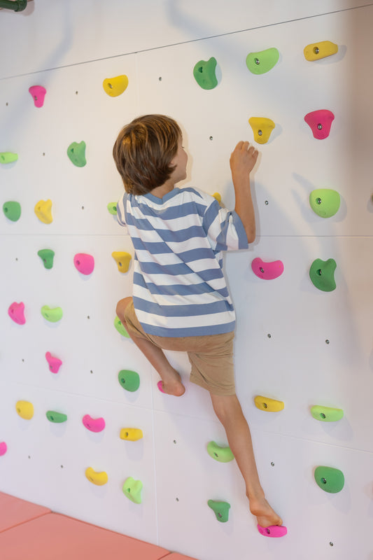 Child climbing on a colorful indoor climbing wall.